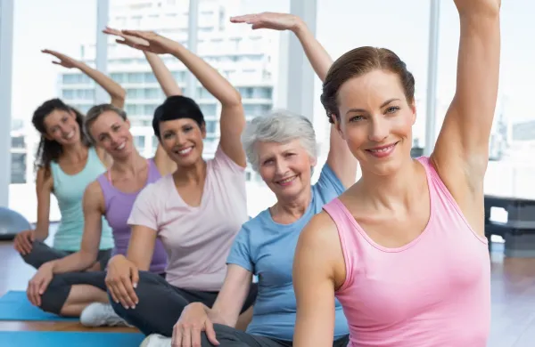Portrait of a smiling trainer with women in row stretching hands at yoga class,Image: 187831793, License: Royalty-free, Restrictions:, Model Release: yes, Credit line: -/Wavebreak/Profimedia