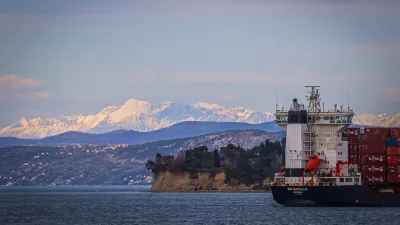 Koper.Tovorna ladja v Koprskem zalivu.Pogled na Debeli rtic, v ozadju Alpe.
