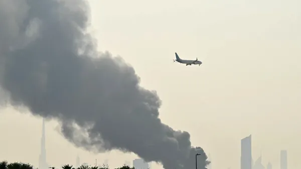 An Emirates aircraft flies past plumes of smoke from an ongoing fire near Dubai International Airport in Dubai on March 16, 2026. Missiles and drone attacks hit across the UAE, with a drone-related incident sparking a fuel tank fire near Dubai airport that disrupted travel, while a missile killed a civilian in Abu Dhabi.,Image: 1083479391, License: Rights-managed, Restrictions: Attention editors: AFP covers the war in the Middle East through its extensive regional network, including bureaus in Tehran, Jerusalem, and several neighboring countries. Since the start of the conflict, journalists have been working under increasingly restrictive conditions. Authorities in several countries have limited reporters' movements, photo and live video coverage from sensitive locations. Some governments and armed groups have banned images of missile or drone strikes and other security-related sites., Model Release: no, Credit line: STR/AFP/Profimedia