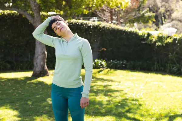 Young adult woman stretching neck on sunlit backyard lawn, enjoying tranquil morning exercise. Activewear, fitness, garden, home workout, flexibility, mobility, wellness,Image: 1002595909, License: Royalty-free, Restrictions:, Model Release: yes, Credit line: -/Wavebreak/Profimedia