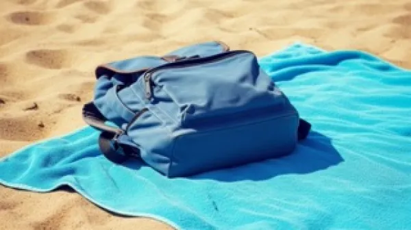 Pe&scaron;čena plaža v mirnem poletnem dnevu.Brisača razgrnjena na toplem pesku.Nahrbtnik pripravljen ob počitku ob morju.